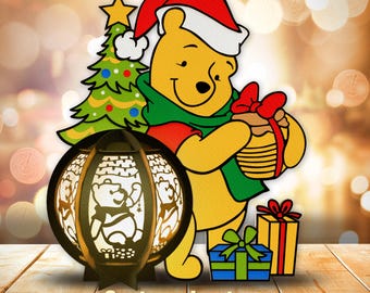 May include: A Christmas-themed wooden lantern featuring a cartoon Winnie the Pooh character wearing a Santa hat and holding a gift. The lantern is decorated with a Christmas tree and presents. The text "Cartoon Lantern" is printed below the lantern.