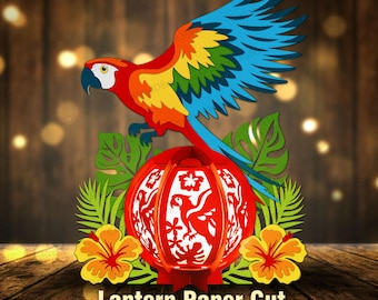 May include: A multi-layered paper cut design featuring a vibrant macaw with blue, yellow, and red feathers perched above a red spherical lantern. The lantern displays intricate cutouts of parrots and hibiscus flowers, flanked by green tropical leaves.