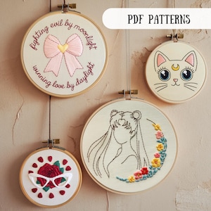 Può includere: Quattro motivi da ricamo su telaio che presentano un fiocco rosa con il testo "fighting evil by moonlight, winning love by daylight", un gatto bianco con occhi blu e una luna crescente, un disegno a linea di una donna con i capelli lunghi e una luna crescente con fiori, e una rosa rossa con occhiali da sole e punti rossi.