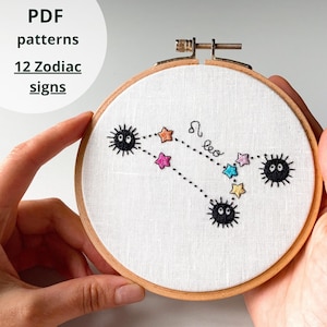 May include: Embroidered hoop art featuring the Leo zodiac constellation. The design includes colorful stars and black, fuzzy creatures connected by dotted lines. The text "PDF patterns 12 Zodiac signs" is visible.