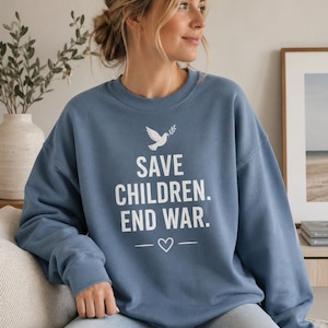May include: A blue sweatshirt featuring the white text "SAVE CHILDREN. END WAR." and a dove graphic. The sweatshirt has a crew neck and a heart symbol. The design is printed on a solid-colored garment.