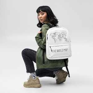 Puede incluir: Mochila blanca con un contorno negro de un mapa del mundo y el texto "THE WORLD MAP".