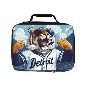 May include: A rectangular black lunch bag featuring a graphic of a tiger wearing sunglasses, a gold chain, and a white baseball jersey with the word Detroit printed on the front. The tiger is shown with its mouth open in a stadium setting.