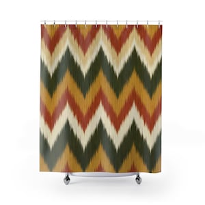 May include: A shower curtain with a repeating chevron pattern in shades of red, green, yellow, and cream. The curtain hangs from a metal rod with silver-colored rings. The design has a textured, woven appearance.