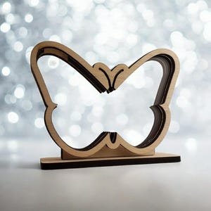 May include: A wooden butterfly-shaped decorative stand with a layered design. The stand is made of light brown wood and has a black base.