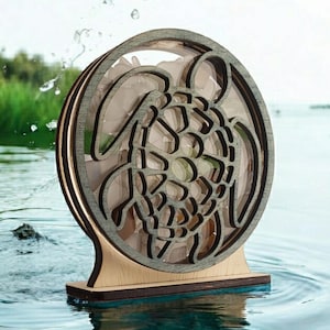 May include: A wooden sea turtle sculpture with a layered design. The turtle is carved in a circular shape and has a light brown finish. The sculpture is sitting on a wooden base and is floating in water.