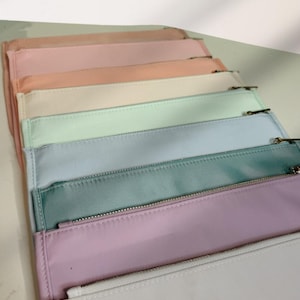 May include: A set of seven zippered pouches in various pastel colors, including pink, peach, cream, light green, light blue, teal, and white.