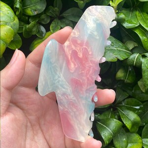 May include: A large, translucent hair claw with a swirl pattern in shades of pink, blue, and white.