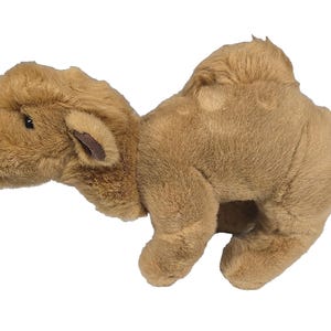 May include: A plush camel toy in a light brown color. The stuffed animal has a soft, furry texture, with detailed features including small ears and a hump. The toy is designed to resemble a camel.