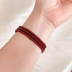 May include: A red beaded bracelet with multiple strands of small, round beads.