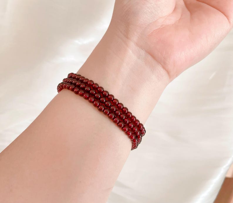 May include: A red beaded bracelet with multiple strands of small, round beads.