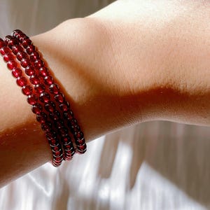 May include: A red beaded bracelet with multiple strands of small, round beads.