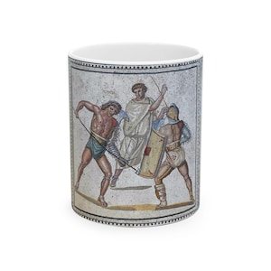Puede incluir: Taza de cerámica blanca con una imagen de estilo mosaico de gladiadores en combate. La obra de arte representa a tres figuras, una con un escudo, luchando con lanzas y espadas. El diseño es en tonos marrones, beige y azules.