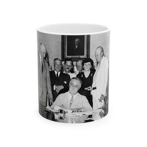 May include: Black and white photograph of a group of people, including President Franklin Delano Roosevelt, signing a document at a table. The photo is taken from a slightly elevated angle, showing the group gathered around the table.