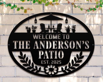 May include: Black metal patio sign with the text "WELCOME TO THE ANDERSON'S PATIO EST. 2025". The sign features a decorative design of a patio scene with chairs, an umbrella, and plants. A floral design is at the bottom.