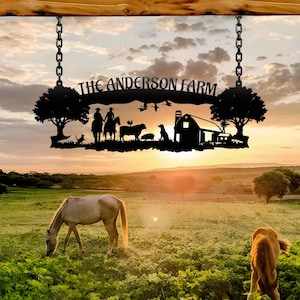 May include: A black metal sign reading "THE ANDERSON FARM" suspended by chains. The sign depicts a farm scene with trees, animals, and a barn against a sunset. Two horses graze in a green field, with a rural landscape in the background.