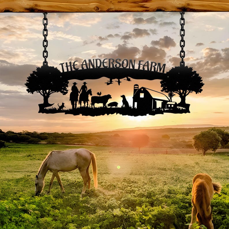 May include: A black metal sign reading "THE ANDERSON FARM" suspended by chains. The sign depicts a farm scene with trees, animals, and a barn against a sunset. Two horses graze in a green field, with a rural landscape in the background.