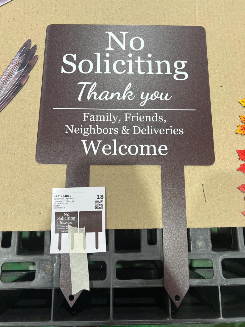 May include: A dark brown metal garden sign with white text that reads: No Soliciting Thank you, Family, Friends, Neighbours & Deliveries Welcome. The sign features two pointed stakes at the bottom for insertion into the ground.