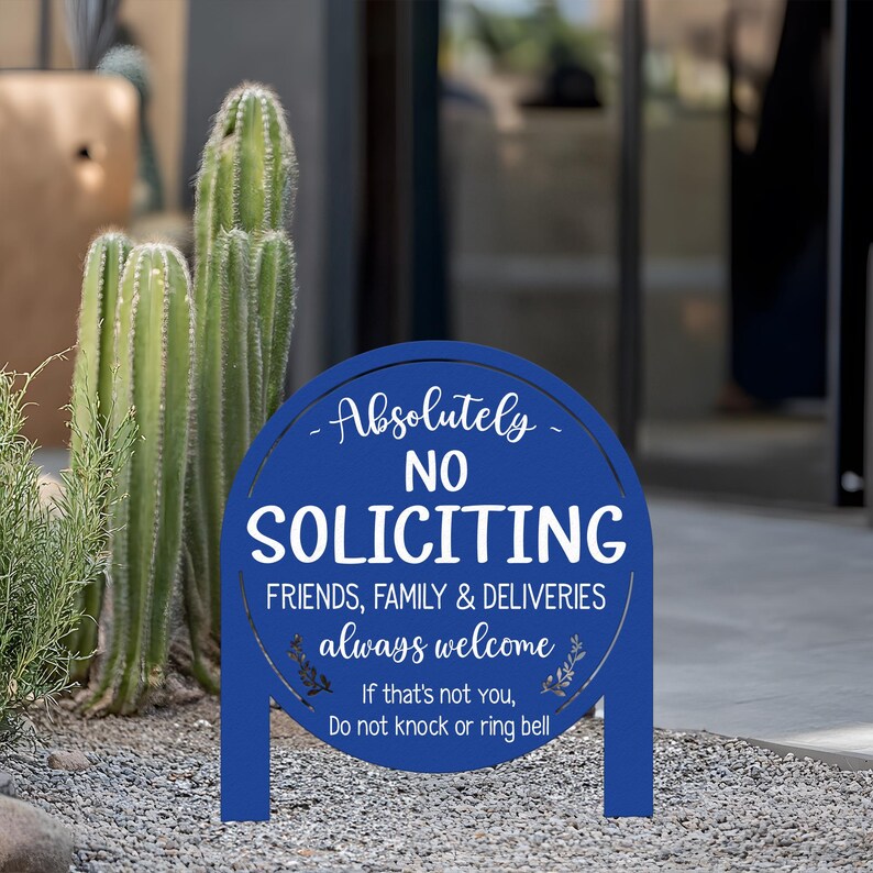 May include: A circular blue metal sign with white text that reads: Absolutely NO SOLICITING. FRIENDS, FAMILY & DELIVERIES always welcome. If that's not you, Do not knock or ring bell. The sign features two legs for ground insertion.