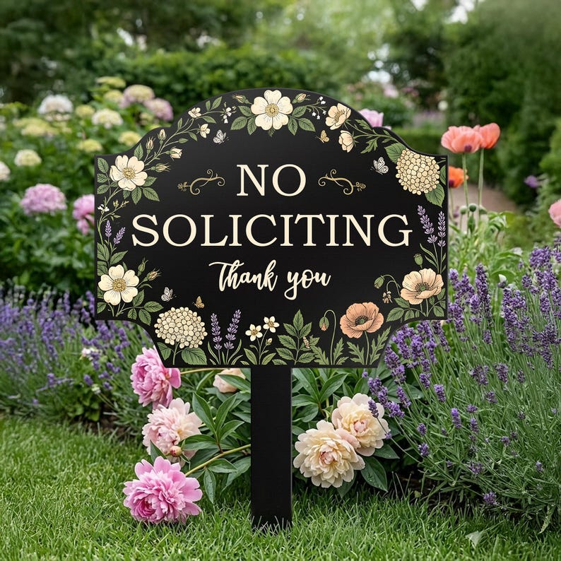 May include: A black garden sign with a scalloped top edge featuring cream, peach, and green floral illustrations. The text reads NO SOLICITING in large capital letters and Thank you in a smaller script font, mounted on a black stake.