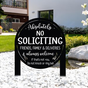 May include: A round black metal yard sign with white text that reads: Absolutely NO SOLICITING, FRIENDS, FAMILY & DELIVERIES always welcome, If that's not you, Do not knock or ring bell. The sign features two small leaf branch icons.