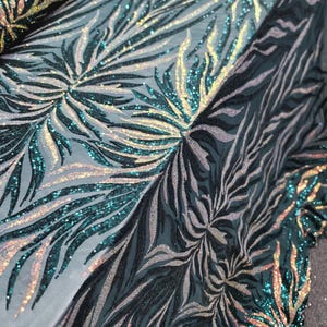 May include: Teal and gold iridescent sequins on a black mesh fabric with a swirling leaf pattern.