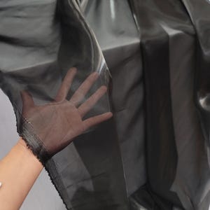May include: Black sheer fabric with a slight sheen. The fabric is translucent and has a soft, flowing texture.