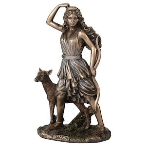 May include: Bronze sculpture of Artemis, the Greek goddess of the hunt, with a bow and arrow, and a deer at her side. The sculpture is on a green base with the word "ARTEMIS" inscribed on it.