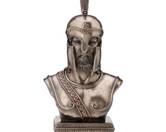 May include: A silver-toned bust of a warrior, featuring a detailed helmet with a plume and a stern facial expression. The bust includes a detailed chest plate and is mounted on a rectangular base, showcasing classical design elements.