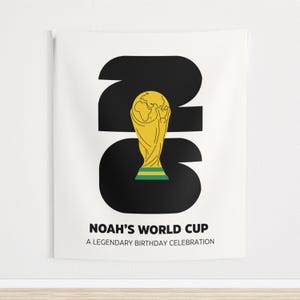 May include: A white wall tapestry featuring a large black number 26 with a yellow and green trophy illustration centered inside. Below the graphic, the text reads NOAH'S WORLD CUP and A LEGENDARY BIRTHDAY CELEBRATION in bold black capital letters.