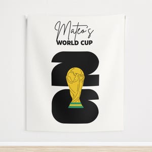 May include: A white rectangular wall tapestry featuring the black text Mateo's WORLD CUP at the top. Below, large black numbers 2026 are displayed, with a yellow and green trophy illustration replacing the zero in the center of the design.
