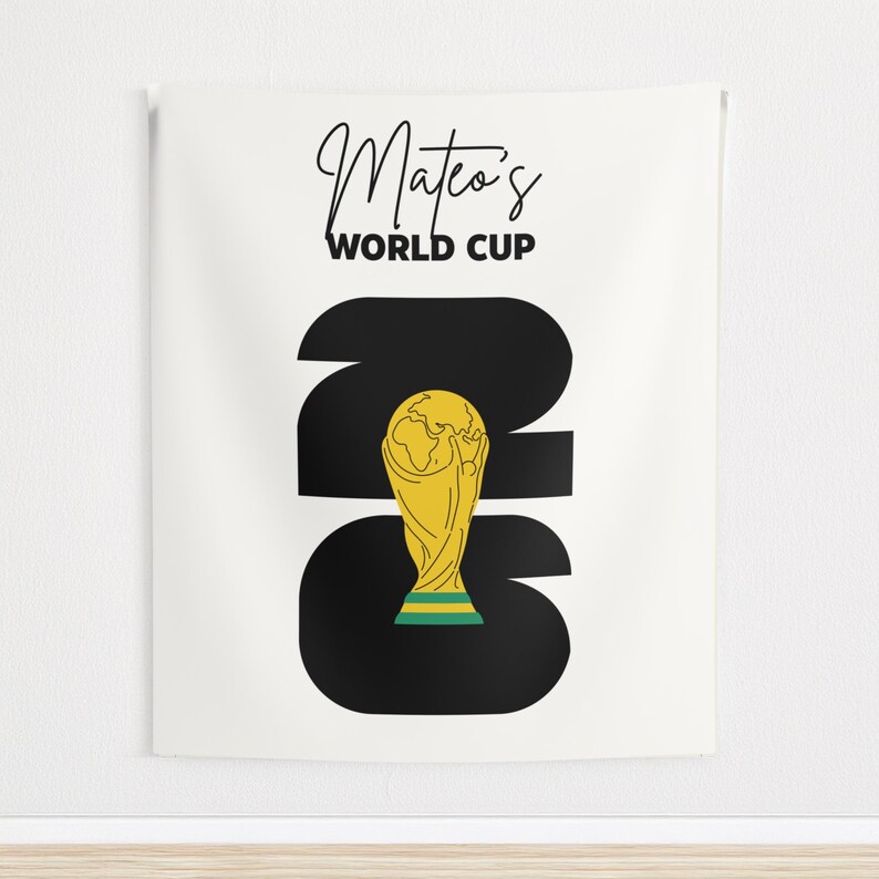 May include: A white rectangular wall tapestry featuring the black text Mateo's WORLD CUP at the top. Below, large black numbers 2026 are displayed, with a yellow and green trophy illustration replacing the zero in the center of the design.