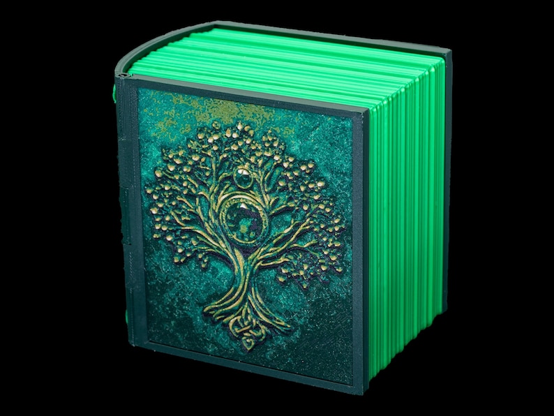 May include: A green book with a gold embossed tree design on the cover. The book is closed and has a spine with multiple ridges.
