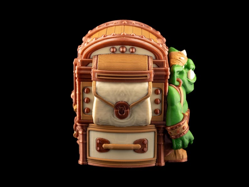 May include: A detailed, fantasy-themed figurine featuring a green orc character leaning against a brown and beige treasure chest. The chest has a hinged lid, a central pouch, and a drawer with a handle. The orc has a gold headband and armbands.