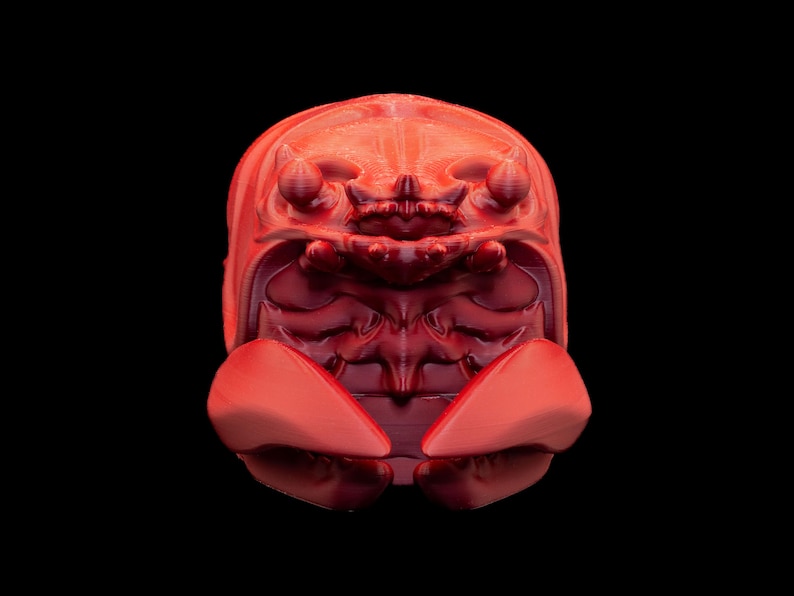 K&ouml;nnte beinhalten: Eine digital gerenderte, rote, insektenartige Skulptur vor schwarzem Hintergrund. Die Skulptur hat einen segmentierten K&ouml;rper mit einem abgerundeten Kopf und zwei gro&szlig;en, fl&uuml;gelartigen Anh&auml;ngen. Die Details deuten auf eine komplexe, strukturierte Oberfl&auml;che hin, wobei der Fokus auf der Form der Kreatur liegt.