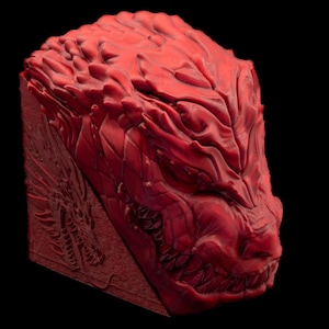 Puede incluir: Un tapón de tecla de cabeza de dragón rojo impreso en 3D con un diseño texturizado detallado. La boca del dragón está abierta, revelando dientes afilados.