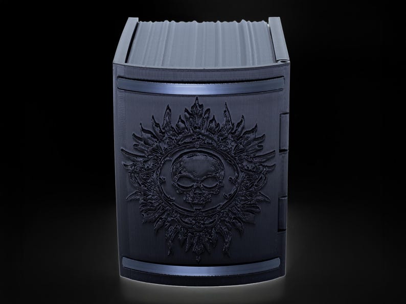 May include: Black card deck box with a skull and sun design.