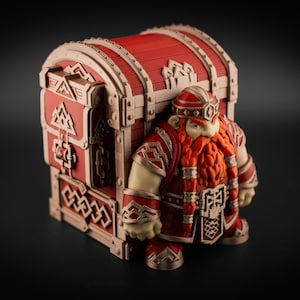 May include: A three-dimensional figurine of a stout dwarf with a long orange beard and red armor, standing in front of a large, red and beige treasure chest. The chest features intricate geometric carvings and a rounded lid design.