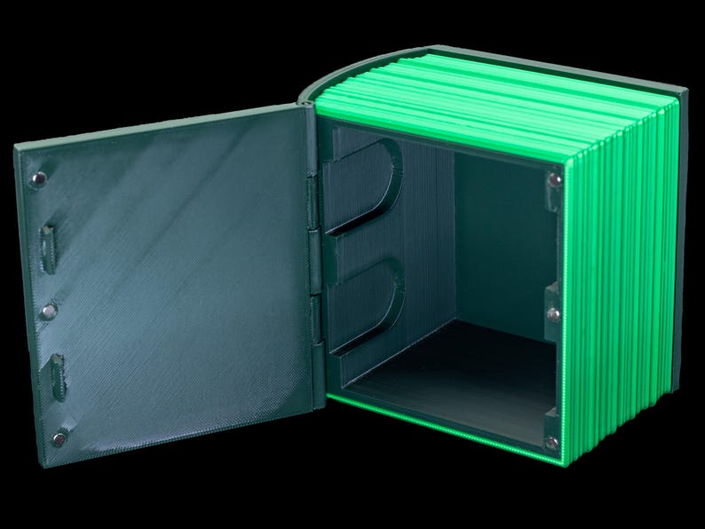 May include: A green and black box with a hinged lid that opens to reveal an empty interior. The box is made of a textured material and has a modern design.