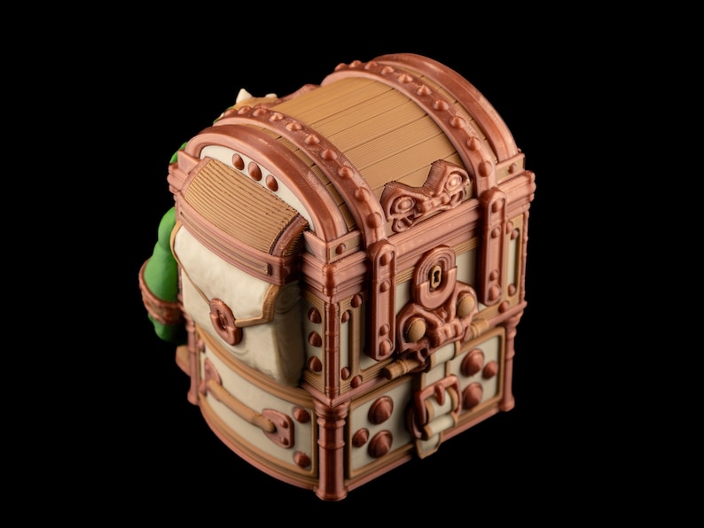 May include: A detailed, decorative treasure chest with a domed lid. The chest features a combination of tan, brown, and cream colors, with ornate metal-like accents. The design includes rivets, a keyhole, and a clasp, suggesting a vintage or fantasy theme.