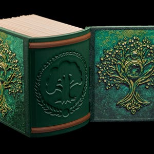 May include: A green leather-bound journal with a gold embossed tree design on the cover. The journal is open to reveal blank pages.