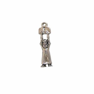 May include: Silver charm of a person holding up two books. The person is wearing a long robe and has a beard.