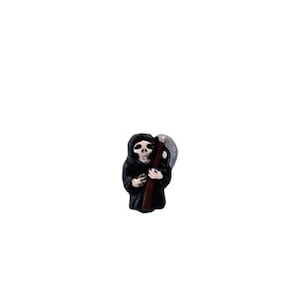 May include: A black figurine of the Grim Reaper holding a scythe. The figurine is made of plastic and has a detailed design.