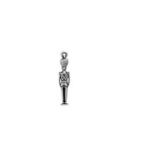 May include: A silver-toned charm in the shape of a toy soldier. The charm features a detailed depiction of a soldier in a uniform with a tall hat. The soldier has a loop at the top for attaching to a bracelet or necklace.