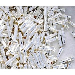 May include: A large pile of silver-colored metal tubes. The tubes are all the same size and shape, and they are arranged in a random pattern.