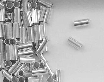 May include: A pile of silver-colored metal crimp beads. The beads are cylindrical and have a smooth, shiny finish.