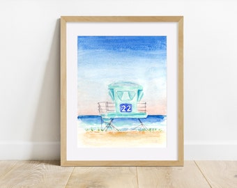 May include: A watercolor painting of a light blue lifeguard stand with the number 22 on it. The stand is on a beach with blue water and a pink and blue sky in the background.