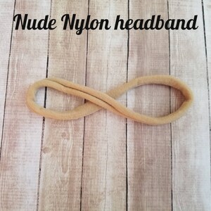 May include: A nude nylon headband, a simple hair accessory, is shown against a light wood background.
