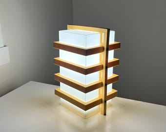 May include: A modern wooden table lamp with a white frosted glass shade. The lamp has a layered design with multiple horizontal wooden slats.
