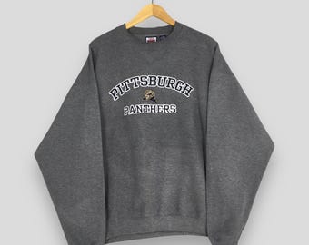 May include: A gray sweatshirt with the text "PITTSBURGH PANTHERS" in white arched lettering. Below the text is the word "PANTHERS" in white block letters. A panther logo is in the center of the arched text.